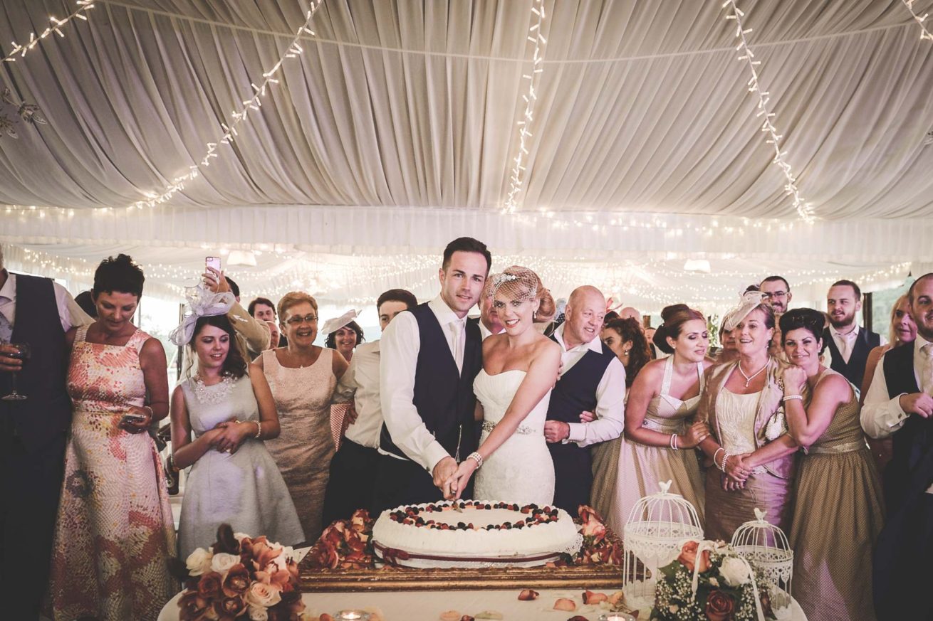 Marquee Wedding Ideas. Bride and groom cutting of the cake inside the marquee.